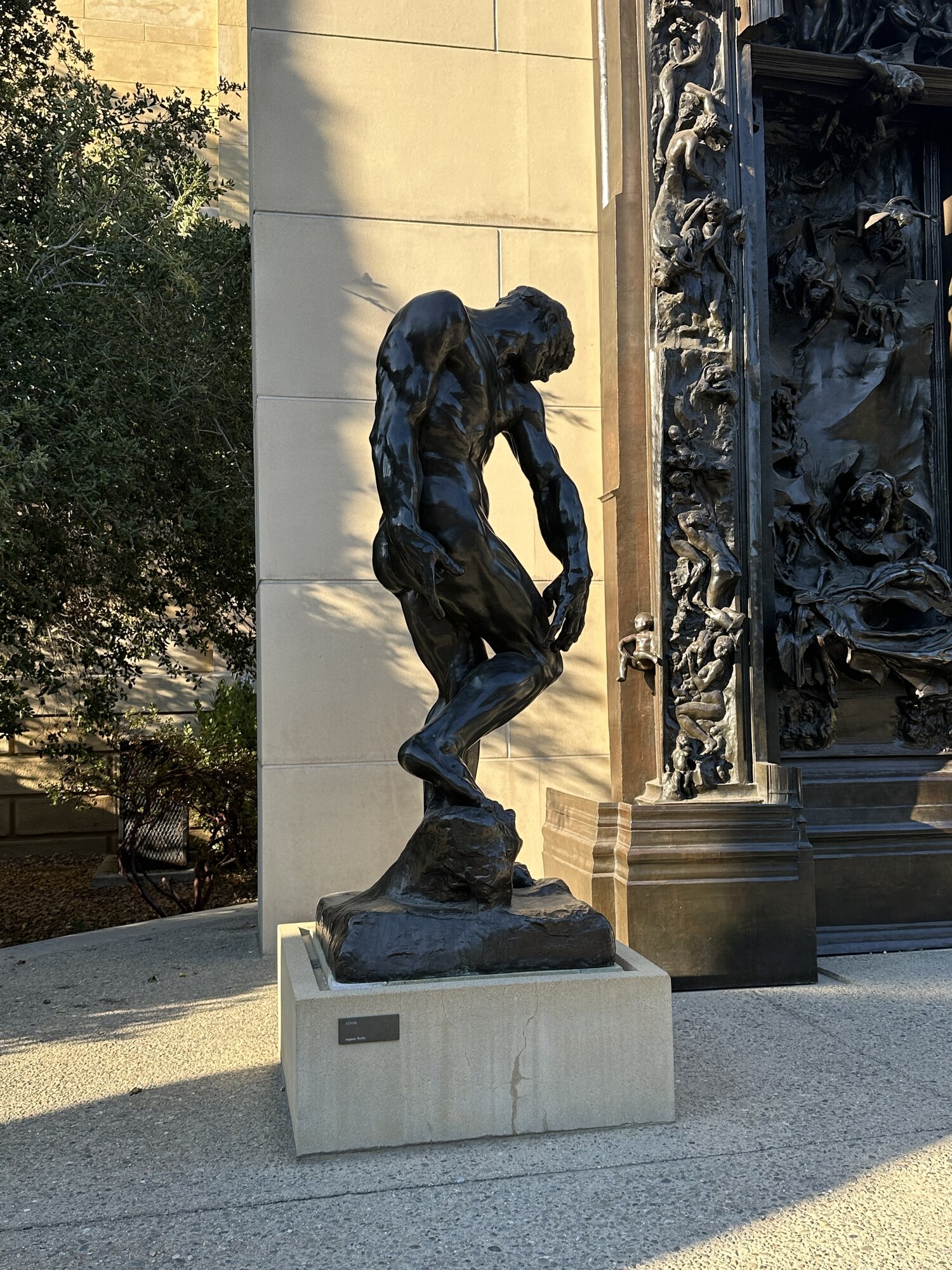 A bent bronze figure beside a sculpted doorway.