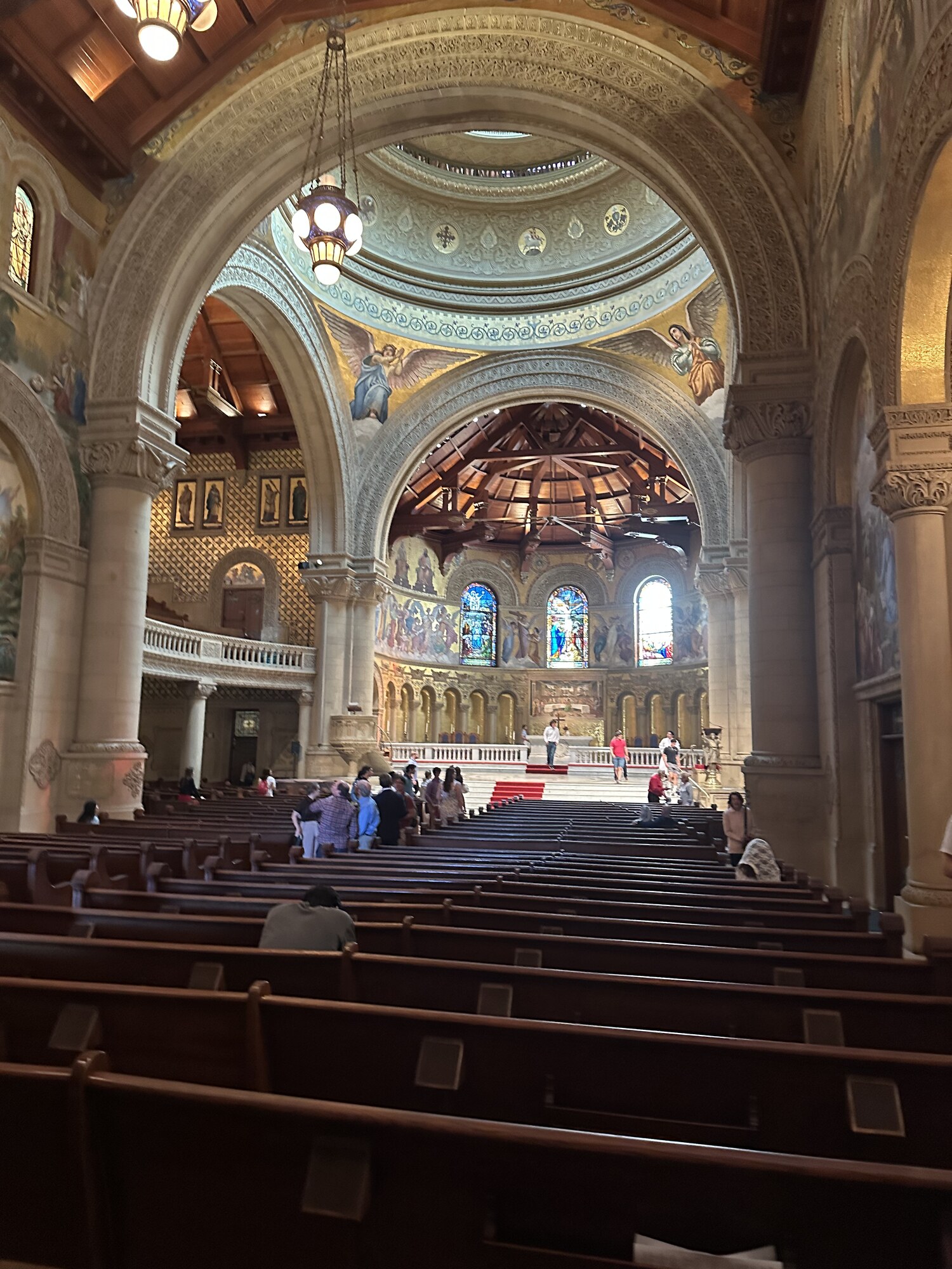 Church pews and visitors beneath a sequence of arches.