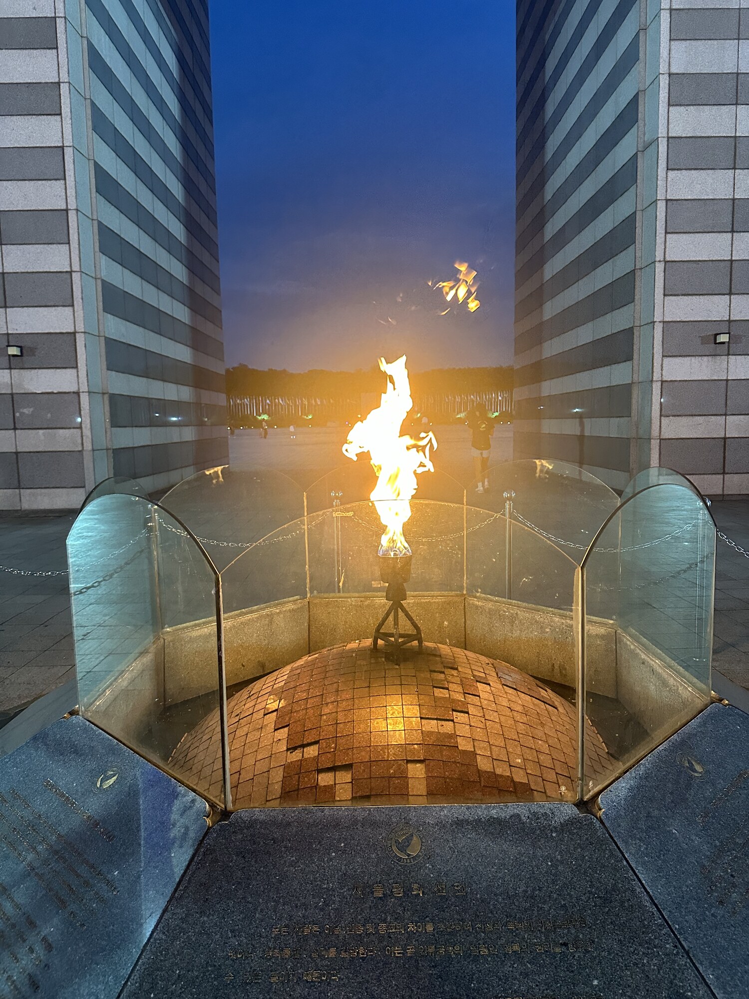 A memorial flame between tall buildings.