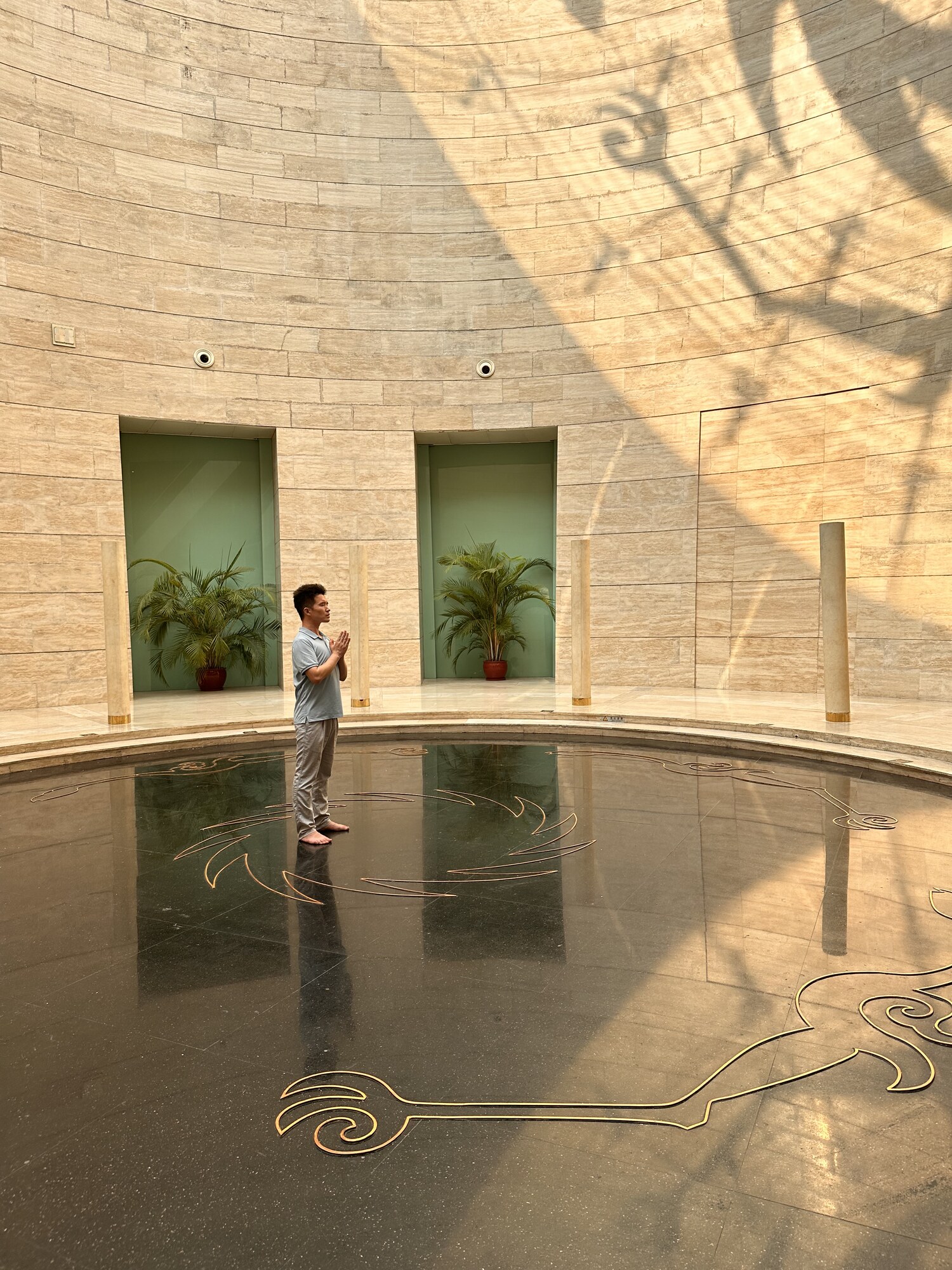 A person and reflections within a circular architectural space.