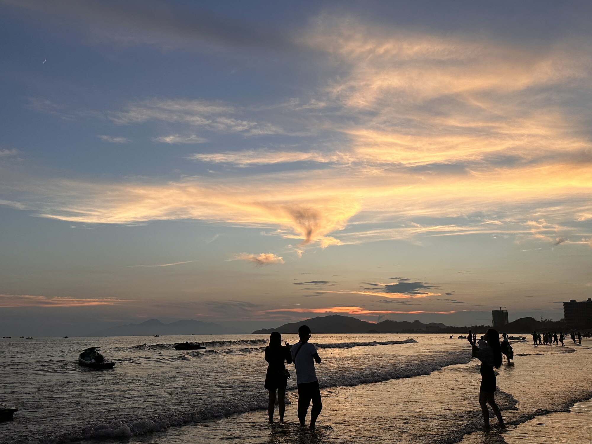 People standing together at the shoreline beneath an evening sky.